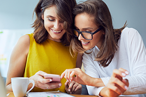 Female friends browsing internt on mobile phone.