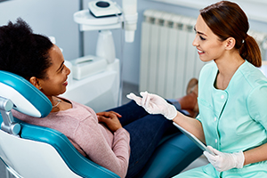 African American woman communicating with her dentist during dental procedure at dentist's office.
