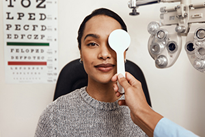 An optometrist covering her patient’s eyes with an occluder during an eye exam.