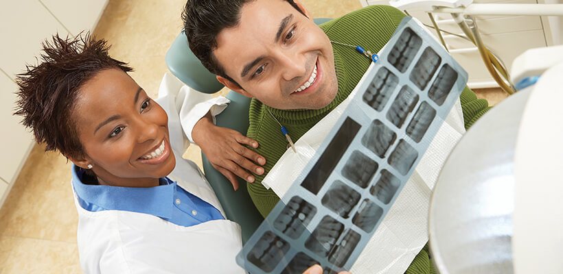 A dentist and her patient look at the patient’s dental x-rays together