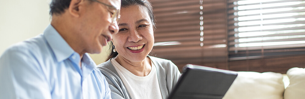 Happy couple laughing and viewing a laptop.