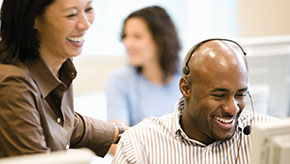 Co-workers smiling and laughing in an office setting.