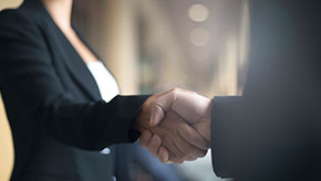 A female and male business colleague shaking hands.