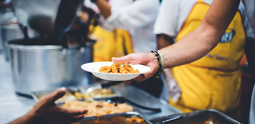 Two people serving food at a shelter.