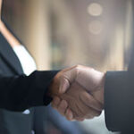 Male and female co-workers shaking hands.