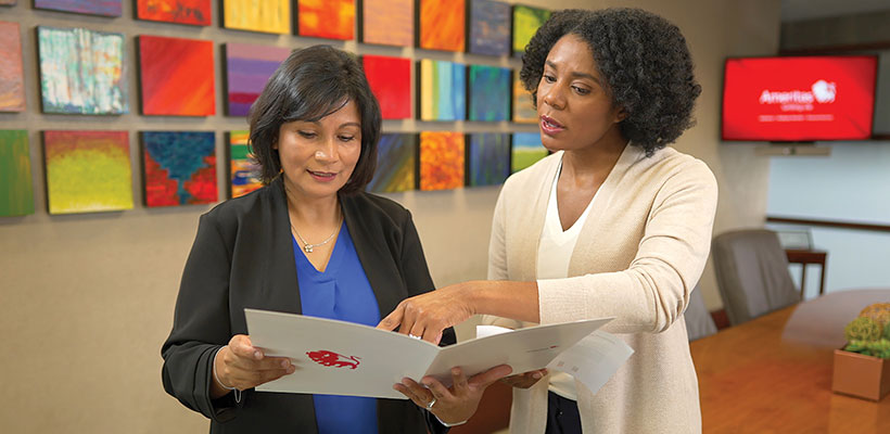 Two professional women looking at document.