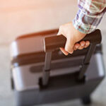 Individual's hand pulling on a piece of luggage.