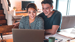 Young couple looking at a laptop and gathering information about auto enrollment.