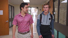 Two male students walking down a school hallway.
