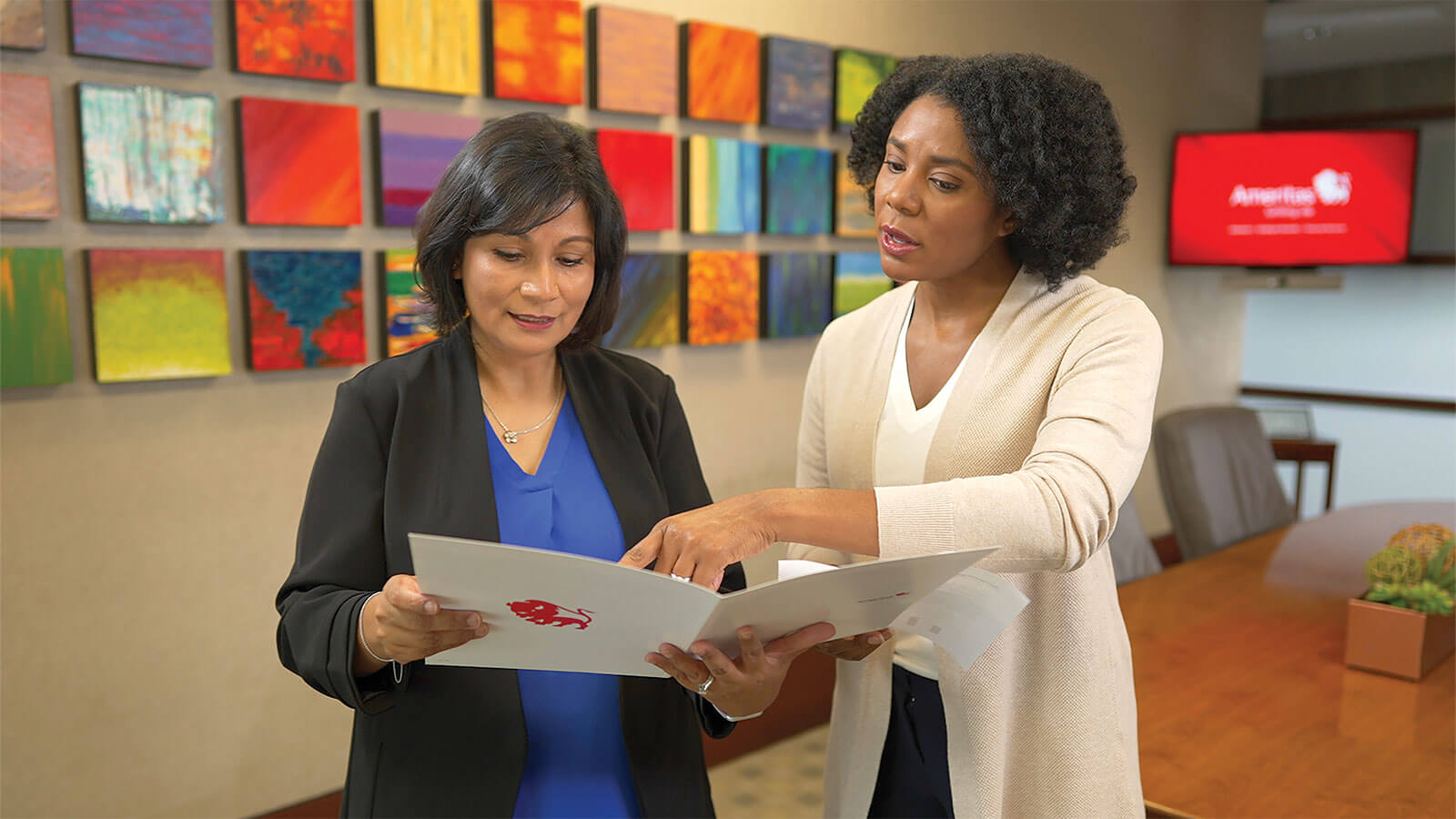 A financial professional explains the benefits of whole life insurance with her client while reviewing the client’s paperwork in a conference room.