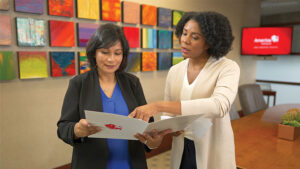 A financial professional explains the benefits of whole life insurance with her client while reviewing the client’s paperwork in a conference room.