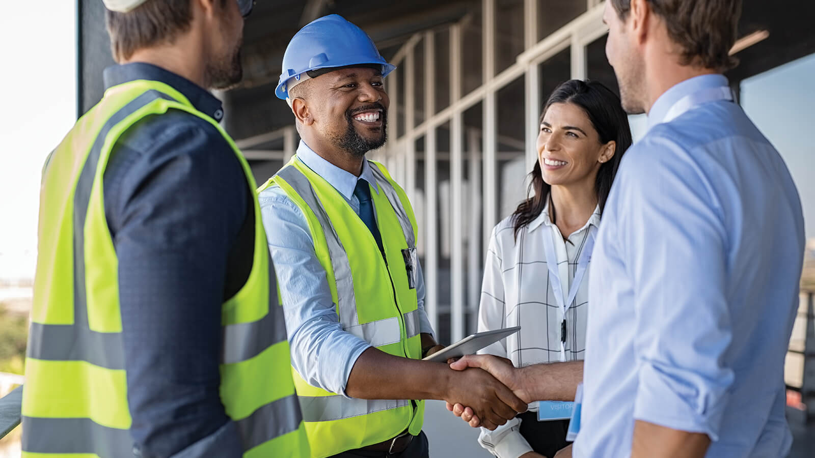 Two construction workers meet with clients to review the building progress and plans.