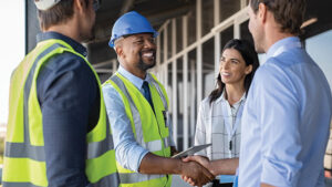 Two construction workers meet with clients to review the building progress and plans.