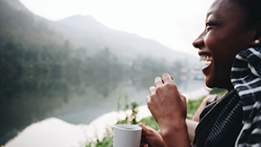 Female enjoying a cup of coffee outside near the mountains.