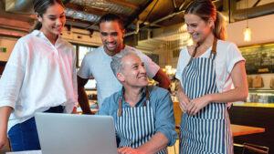 Restaurant owner working with employees at a computer