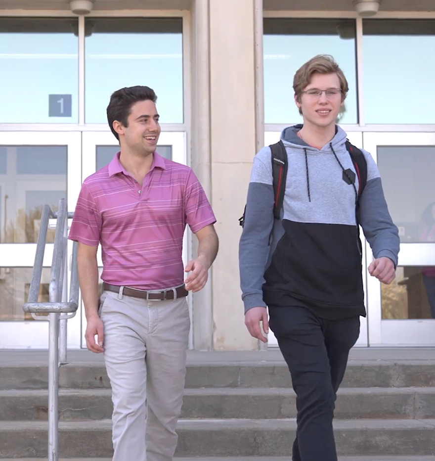 Education Two students walk and talk outside school building