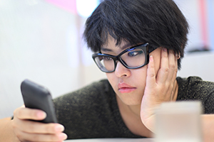 Short haired female with glasses looking at cell phone.