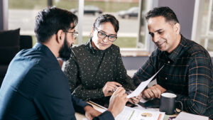 Three people read financial newspapers.