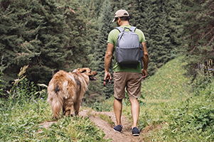 A man and his dog hiking on a trail.