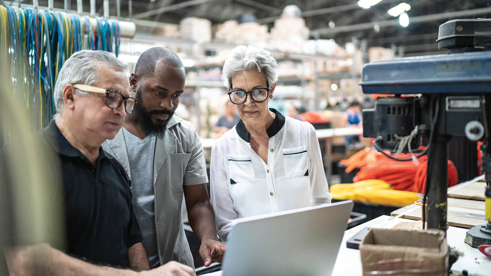 Three warehouse employees looking at a laptop.