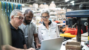 Three warehouse employees looking at a laptop.