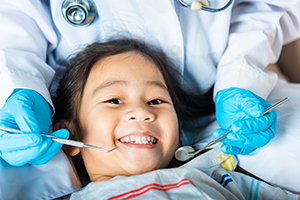 Child in dental chair smiles during examination.