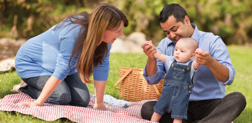 Parents with toddler child enjoying a picnic.