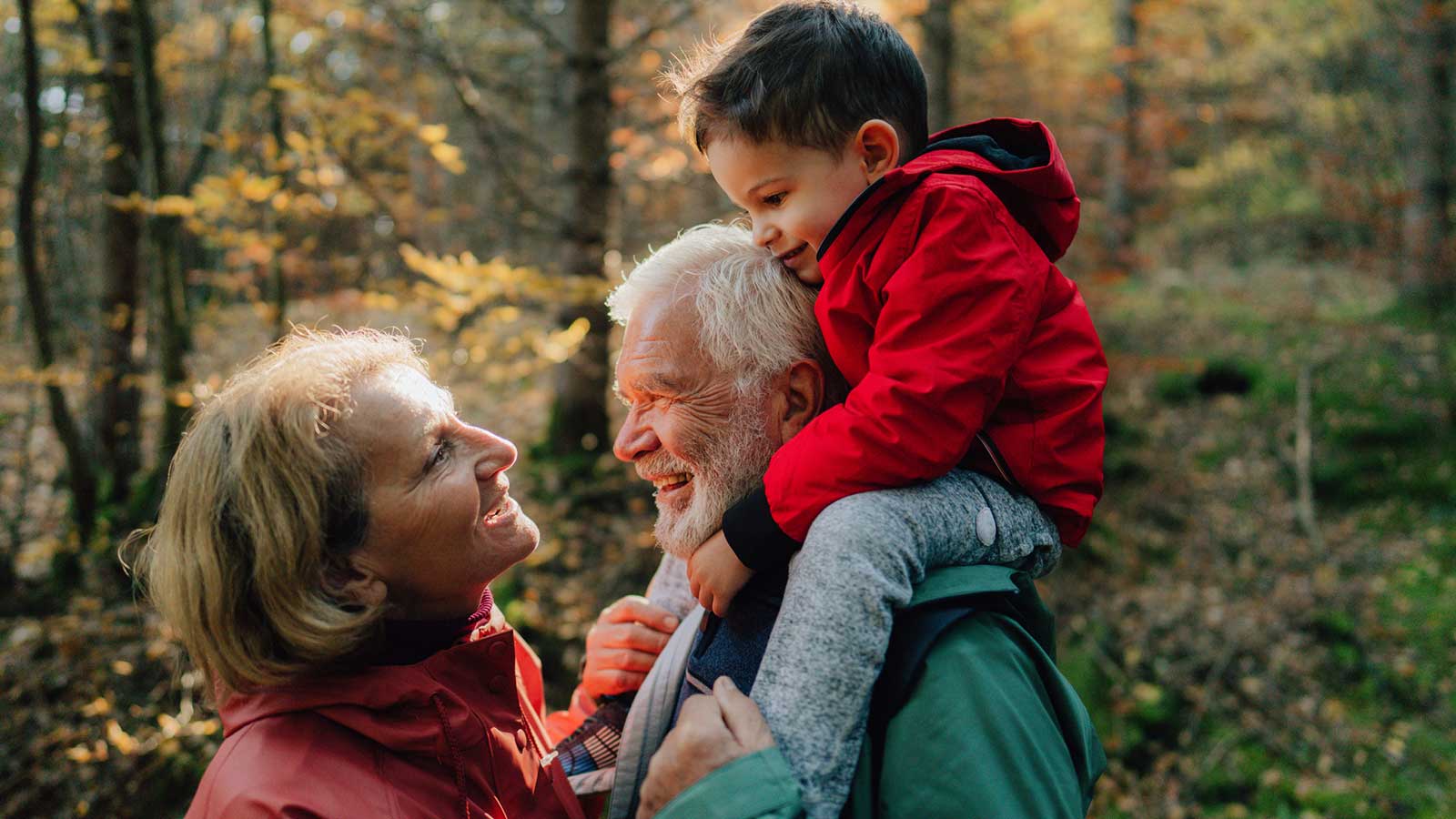 Grandparents enjoy a hike in the forest with their young grandson.