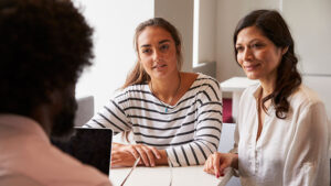 A young woman and her mother meeting with a college admissions counselor.