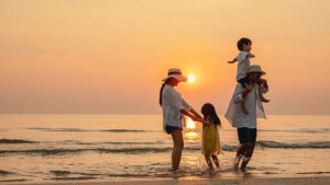A mom and dad play with their young son and daughter on the beach at sunset. They’re relaxed knowing they’re using life insurance in their financial strategy.
