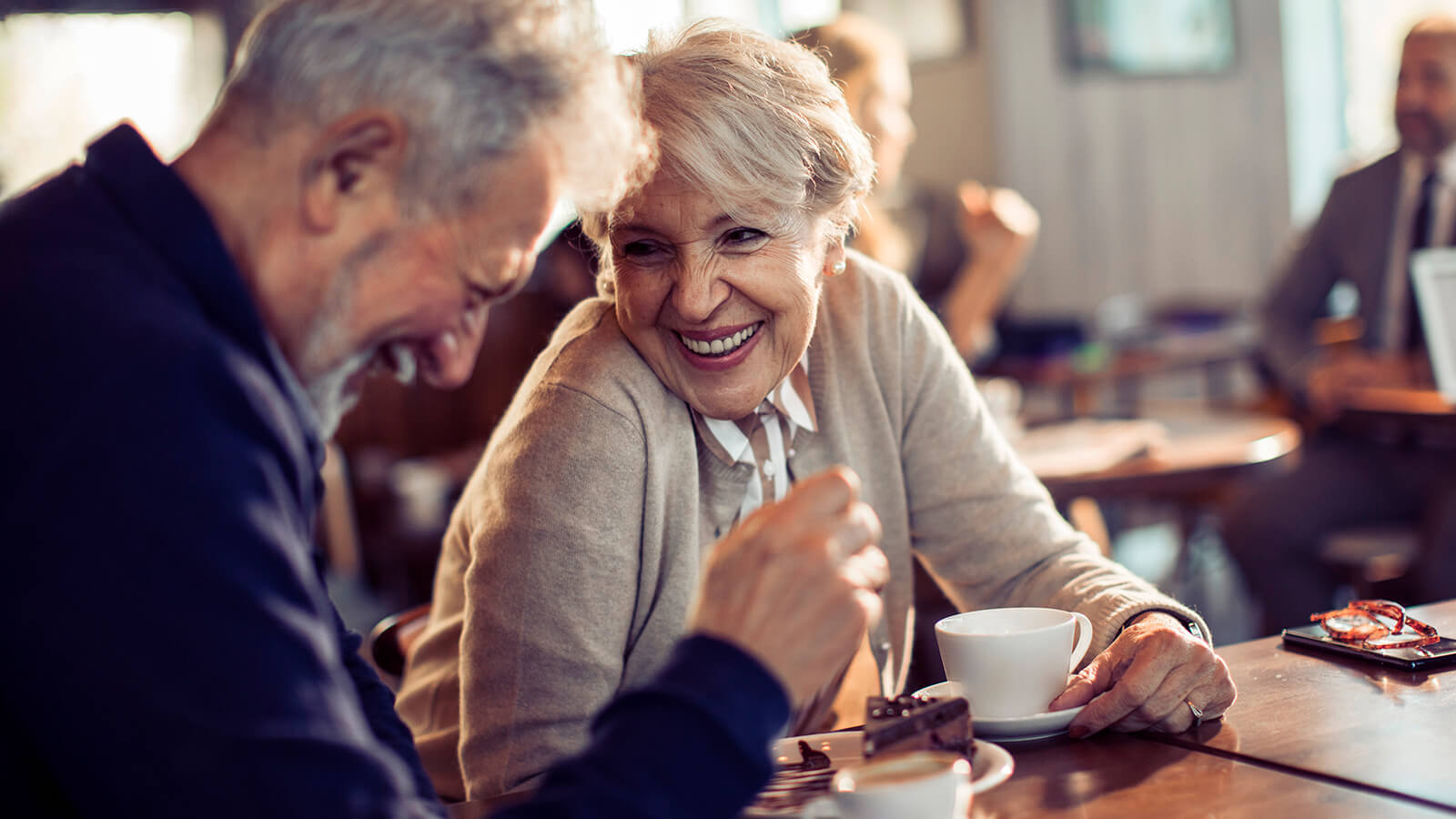 Elderly couple laughing and enjoying coffee.
