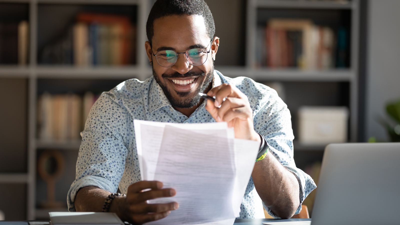 Happy African-American male sitting at a table reviewing papers.