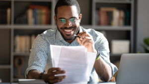 Happy African-American male sitting at a table reviewing papers.