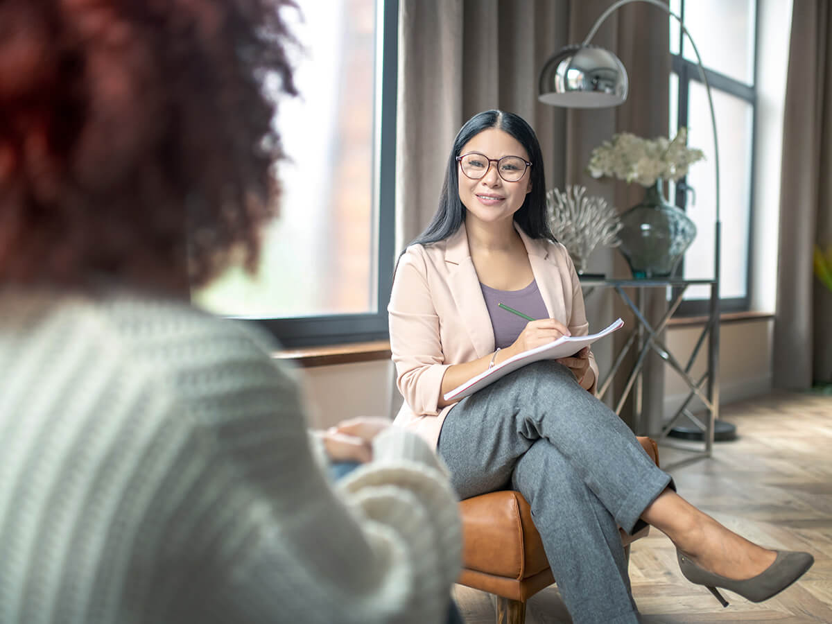 Two females sitting in chairs discussing why employee mental health benefits are essential.