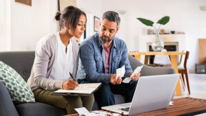 A husband and wife review receipts and financial statements to prepare their end-of-year taxes.