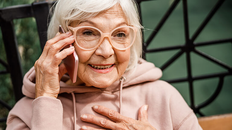 Elderly woman smiling and talking on her cell phone.