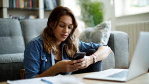 A young woman researches IRAs on her phone to learn the best options to meet her financial goals.