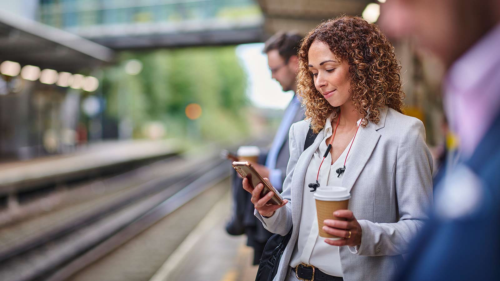 Smiling female looking at cell phone while waiting for subway.