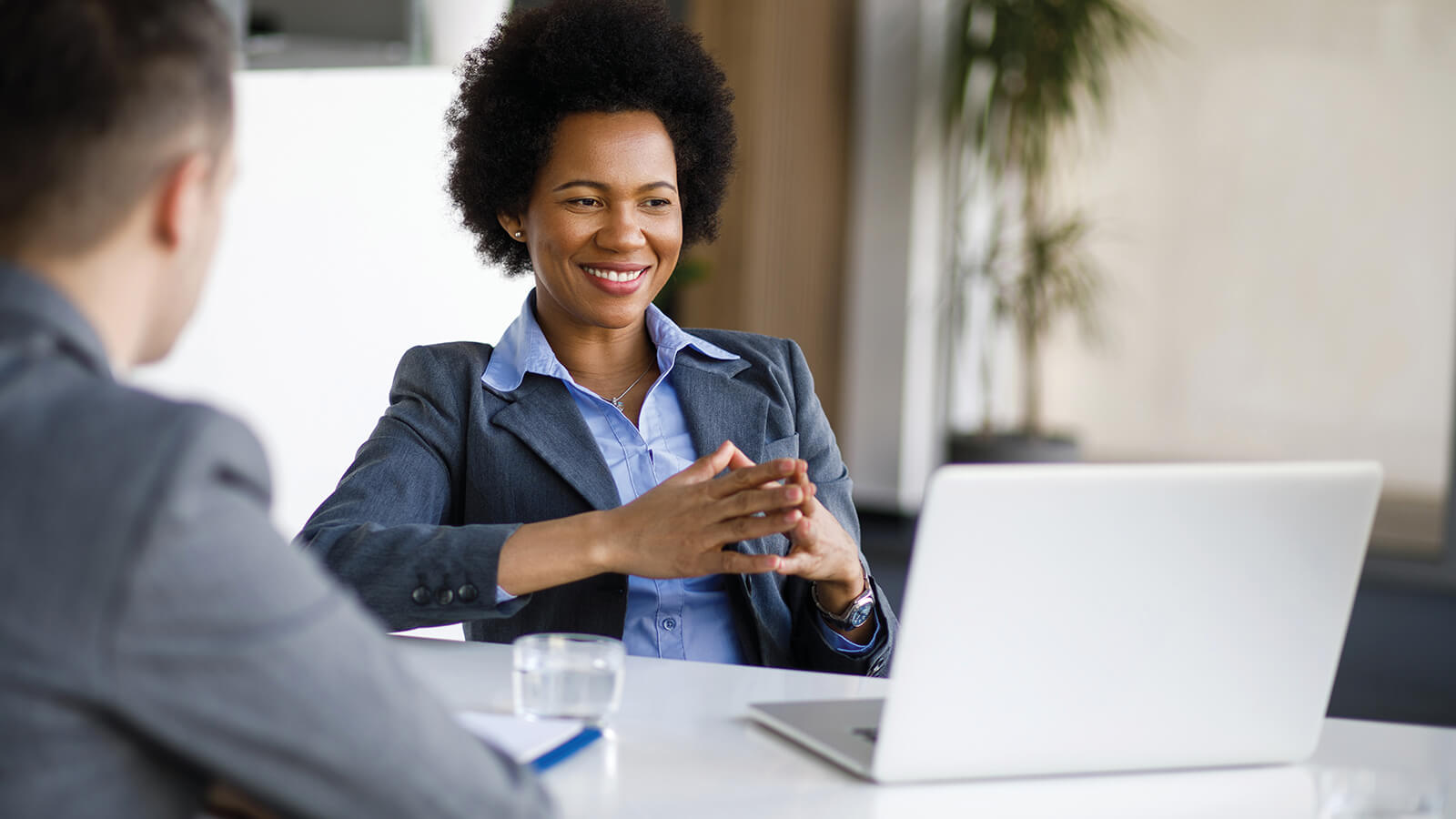 A young professional woman looks at her laptop screen while meeting with a financial professional to learn how to start investing.