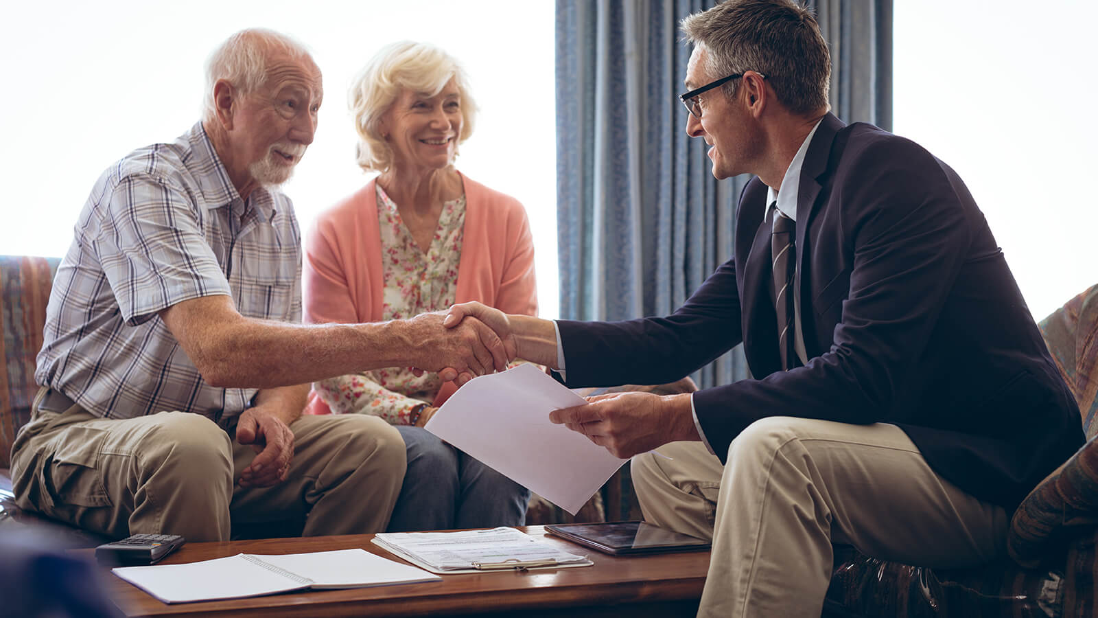 ): A financial professional meets with his clients, a husband and wife in their 70s, to discuss financial strategies to help cover the cost of a serious illness.