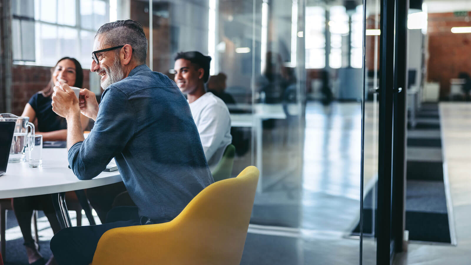 A group of smiling employees at a professional employer organization sit around a conference table discussing their pooled employer plan offering. A group of smiling employees at a professional employer organization sit around a conference table discussing their pooled employer plan offering.