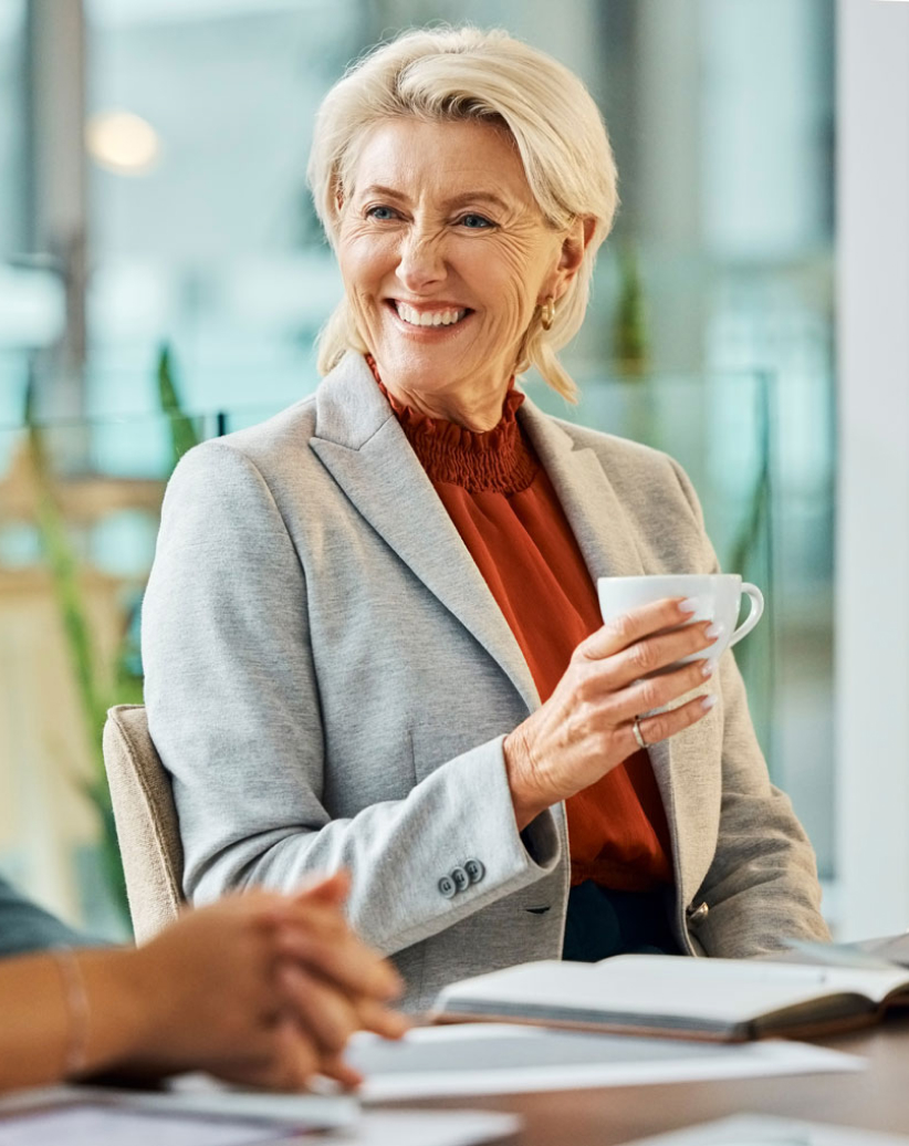 Two female colleagues sitting at a table, smiling and discussing business. Two female colleagues sitting at a table, smiling and discussing business.