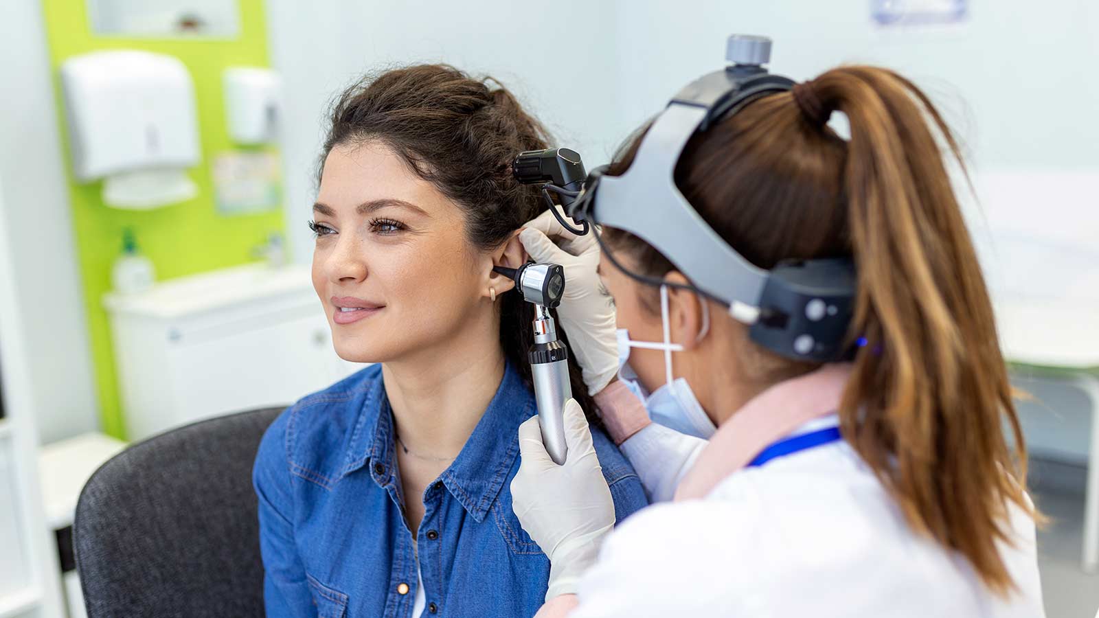Eye doctor checking woman's ear using otoscope at medical clinic. Eye doctor checking woman's ear using otoscope at medical clinic.