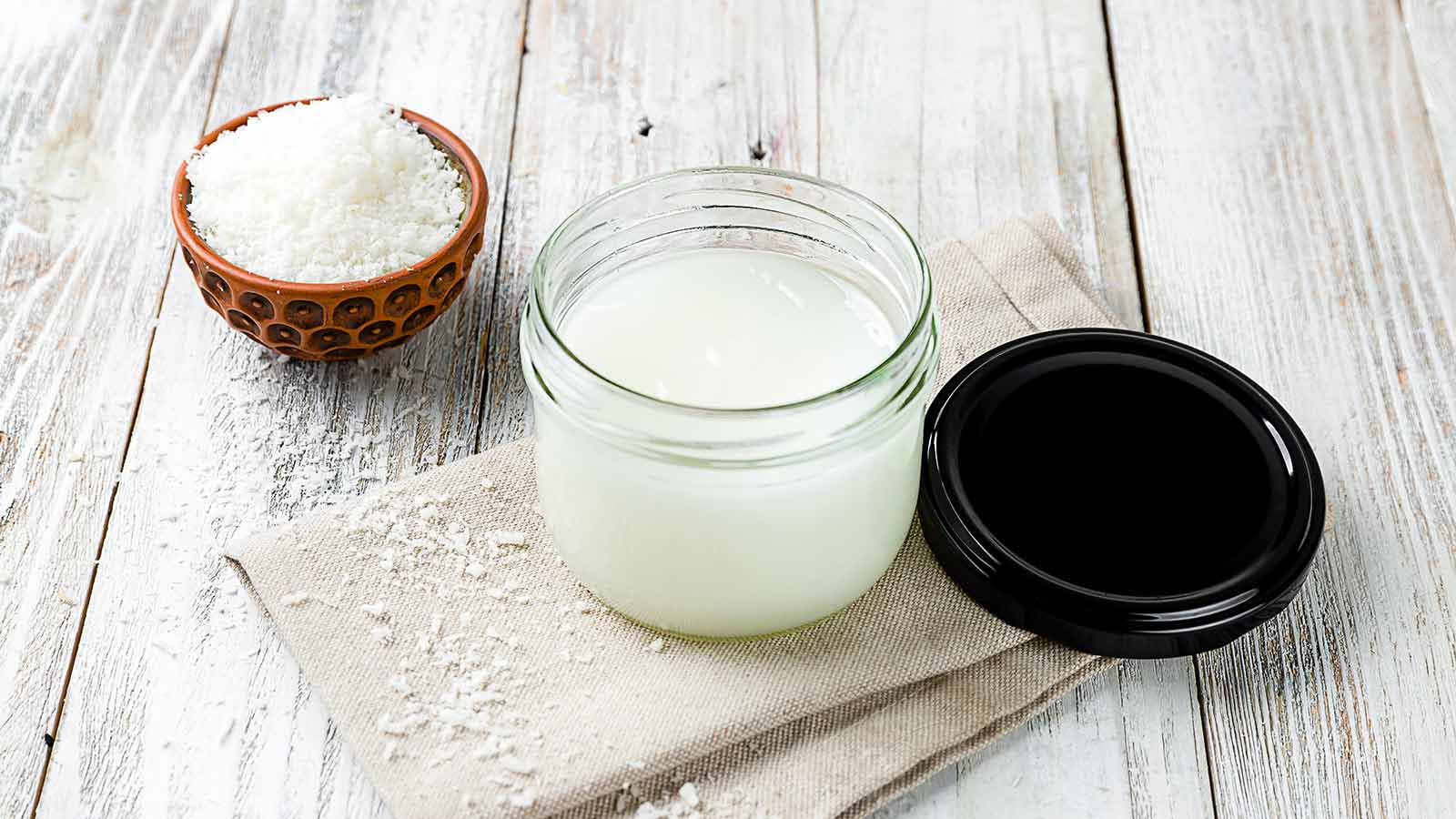 Coconut oil cream on bowl on white wooden table Coconut oil cream on bowl on white wooden table