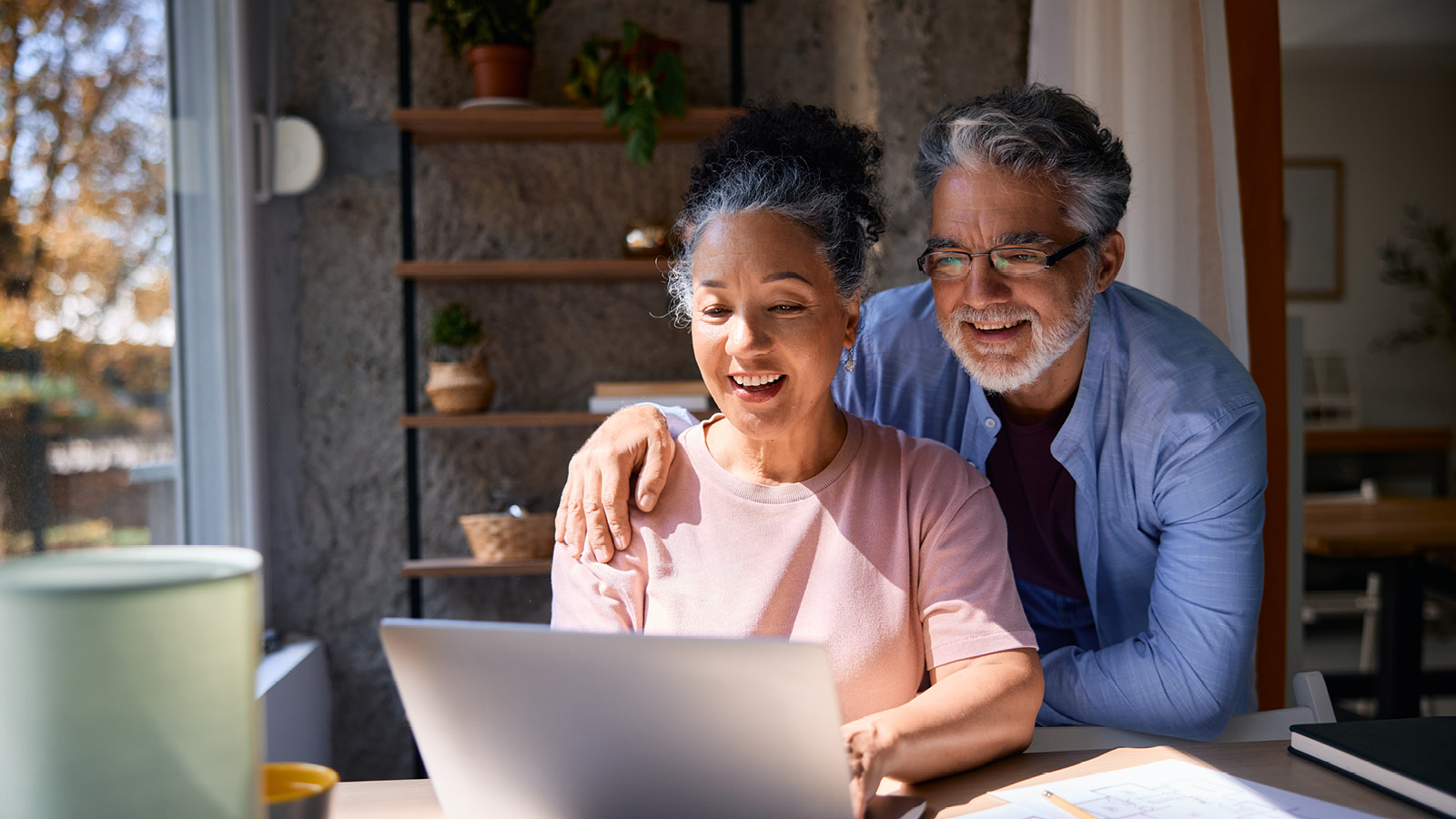 A retired husband and wife look at a laptop screen in their home reviewing their annuity information.