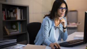 A financial professional looks at her computer screen in her office reviewing beneficiary IRA RMD rules.