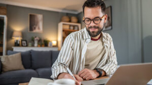 A man in his 30s reviews his retirement resolutions on his laptop at home.