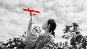 Mother holding son who is holding a toy airplane.