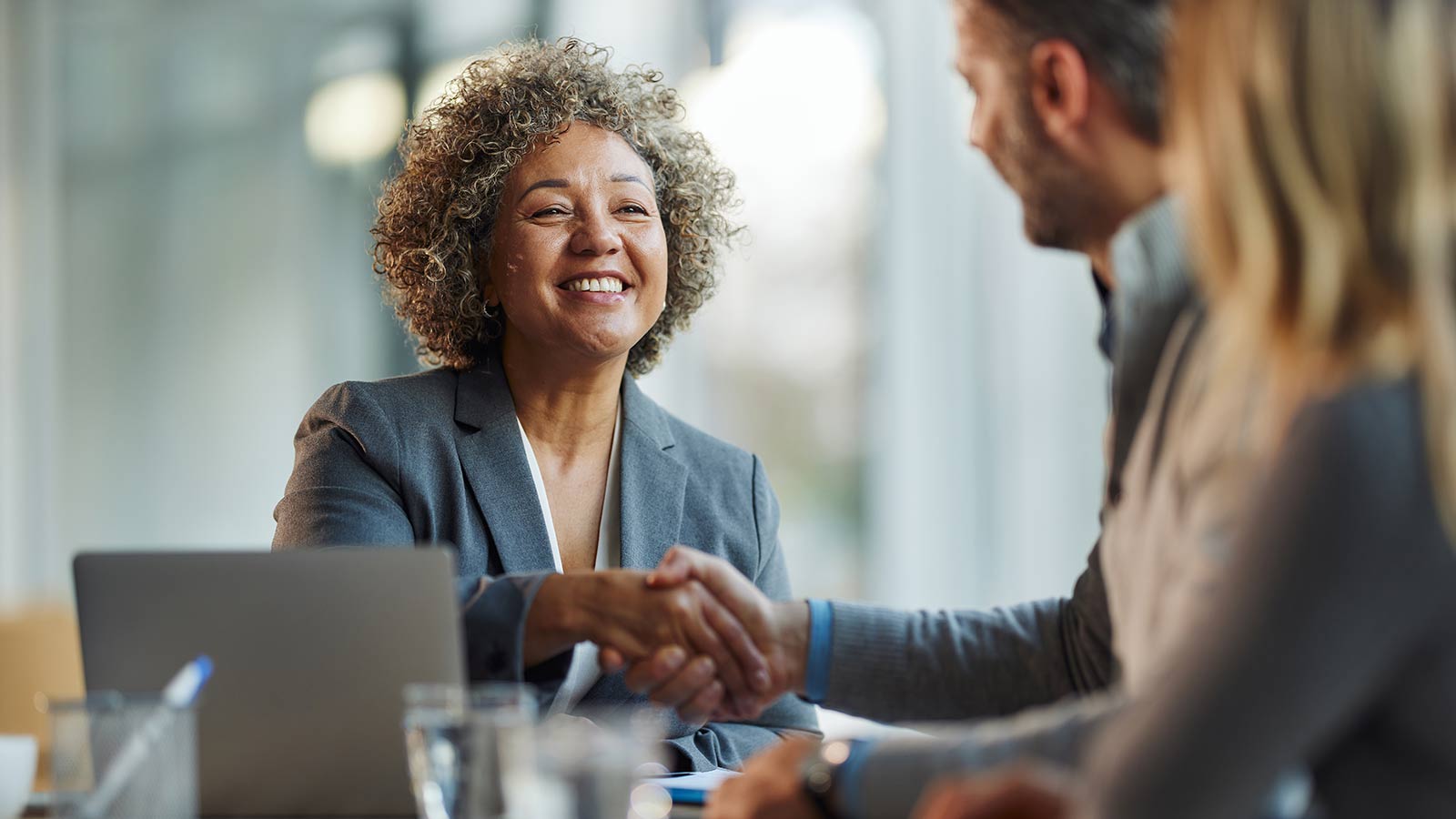 Happy insurance agent shaking hands with her customers in the office.