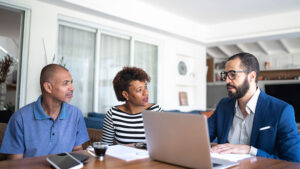 A husband and wife in their 50s meet with their financial professional in their home to discuss converting term life insurance to permanent.